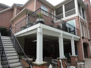 Elevated deck with wrought iron railing and covered patio below by Norm Hughes Homes.