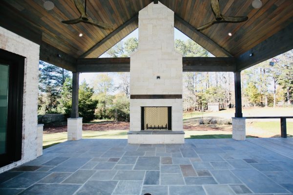 Custom covered outdoor living area with stone fireplace by Norm Hughes Homes.