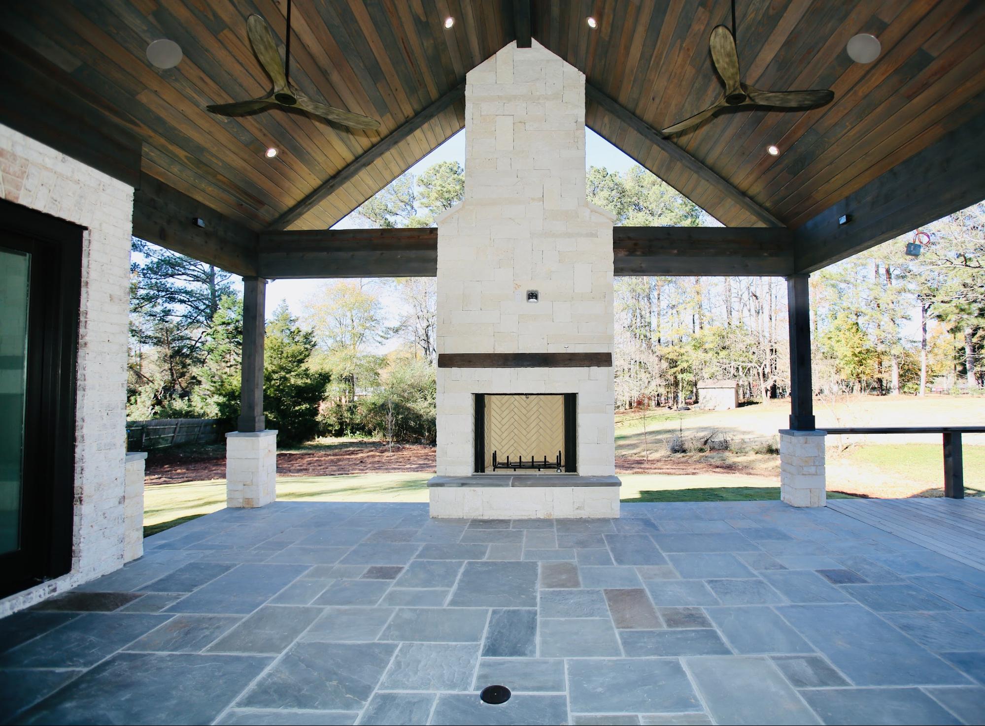 Custom covered outdoor living area with stone fireplace by Norm Hughes Homes.