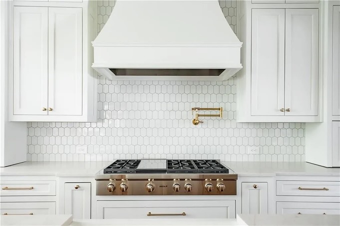 Luxury kitchen with custom vent hood, professional-grade range, and designer backsplash