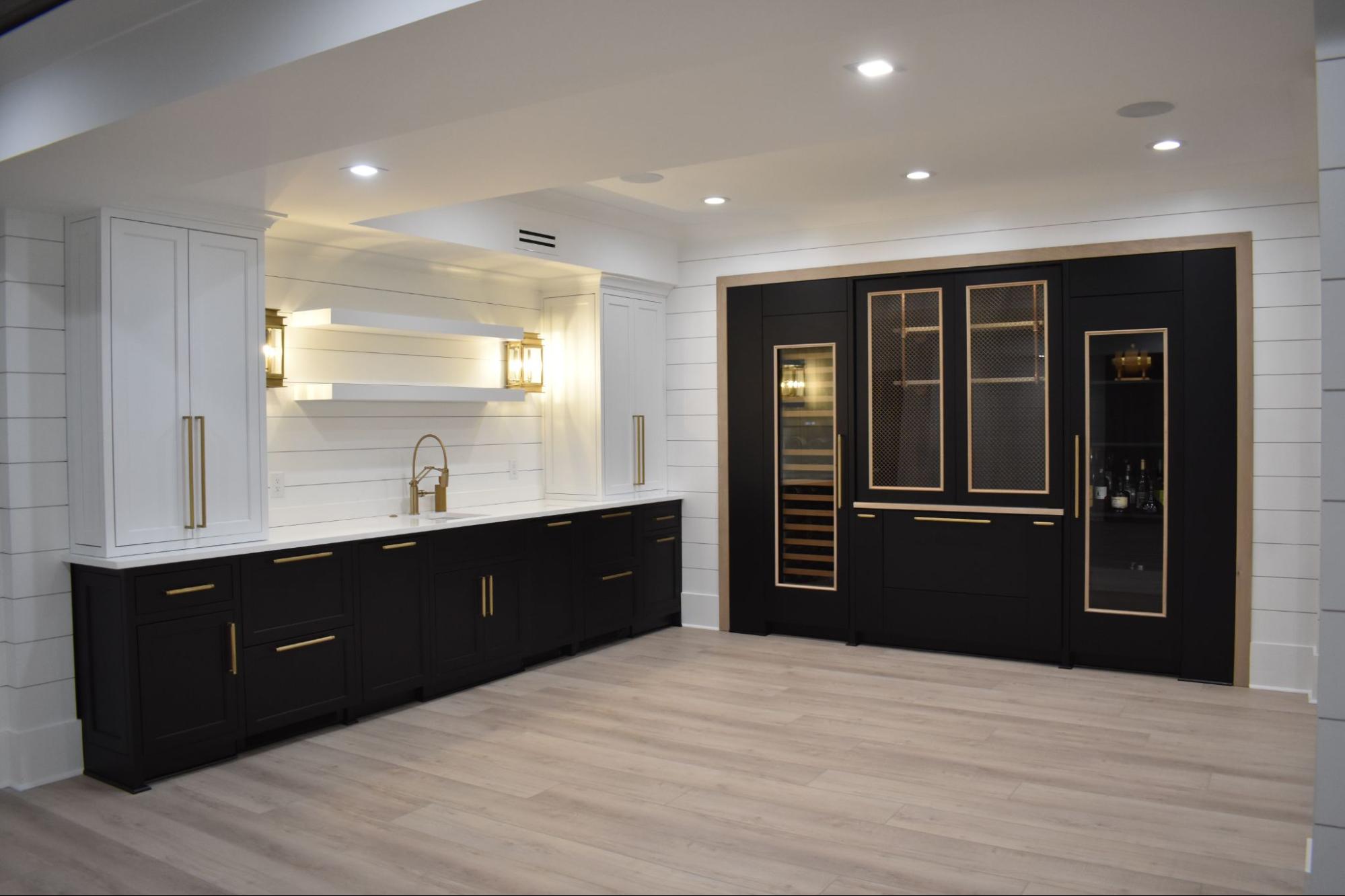 Modern basement wine cellar with black cabinetry, gold accents, and white shiplap wall details.