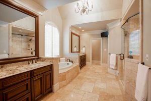  Traditional bathroom remodel with wood vanity, stone tile floors, and soaking tub