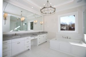 Bright white bathroom remodel with double vanity, built-in tub, and classic lighting