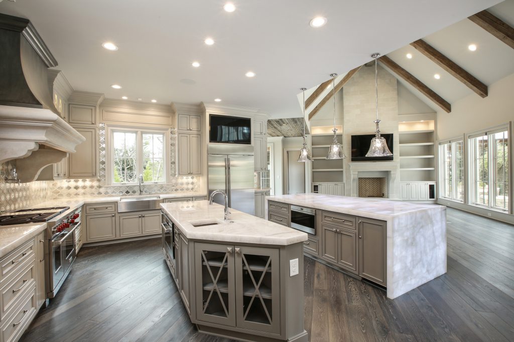 Luxury open-concept kitchen with a double island and vaulted wood-beamed ceilings. image description: A spacious chef's kitchen featuring dual islands, a professional range hood, and elegant pendant lighting set against a backdrop of rustic ceiling beams.