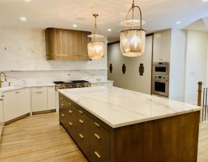Modern kitchen remodel featuring a large wood-finish island and white marble countertops. 