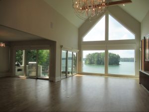 Vaulted living room of a custom lake house with massive windows overlooking a private island on the water.