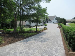 Long custom paver driveway leading to a modern white and black custom lake house estate.