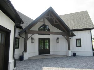 High-contrast front entrance of a mountain-modern custom lake house with dark timber brackets.