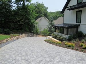 Patterned paver driveway leading to a mountain-modern custom home with manicured landscaping.