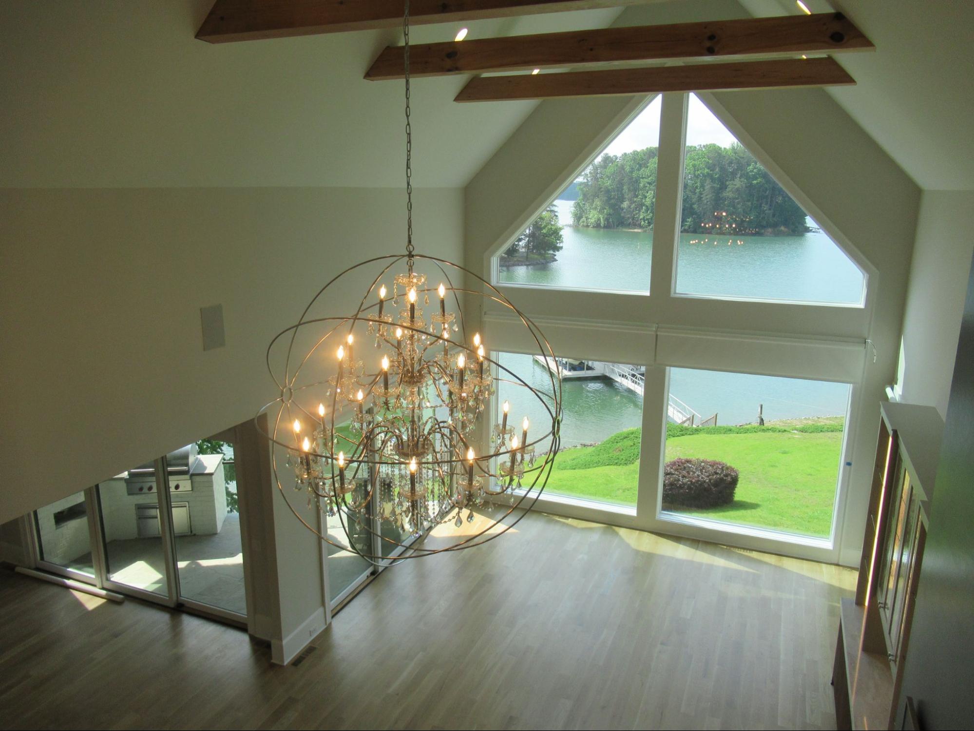 Custom lake house great room with a dramatic black fireplace, floating staircase, and large crystal orb chandelier.