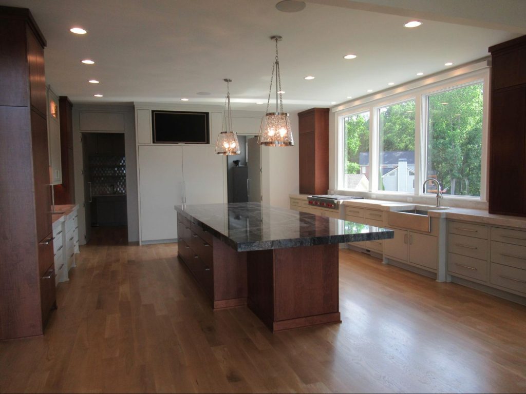Luxury custom lake house kitchen with dark wood cabinets, a massive granite island, and lake-view windows.